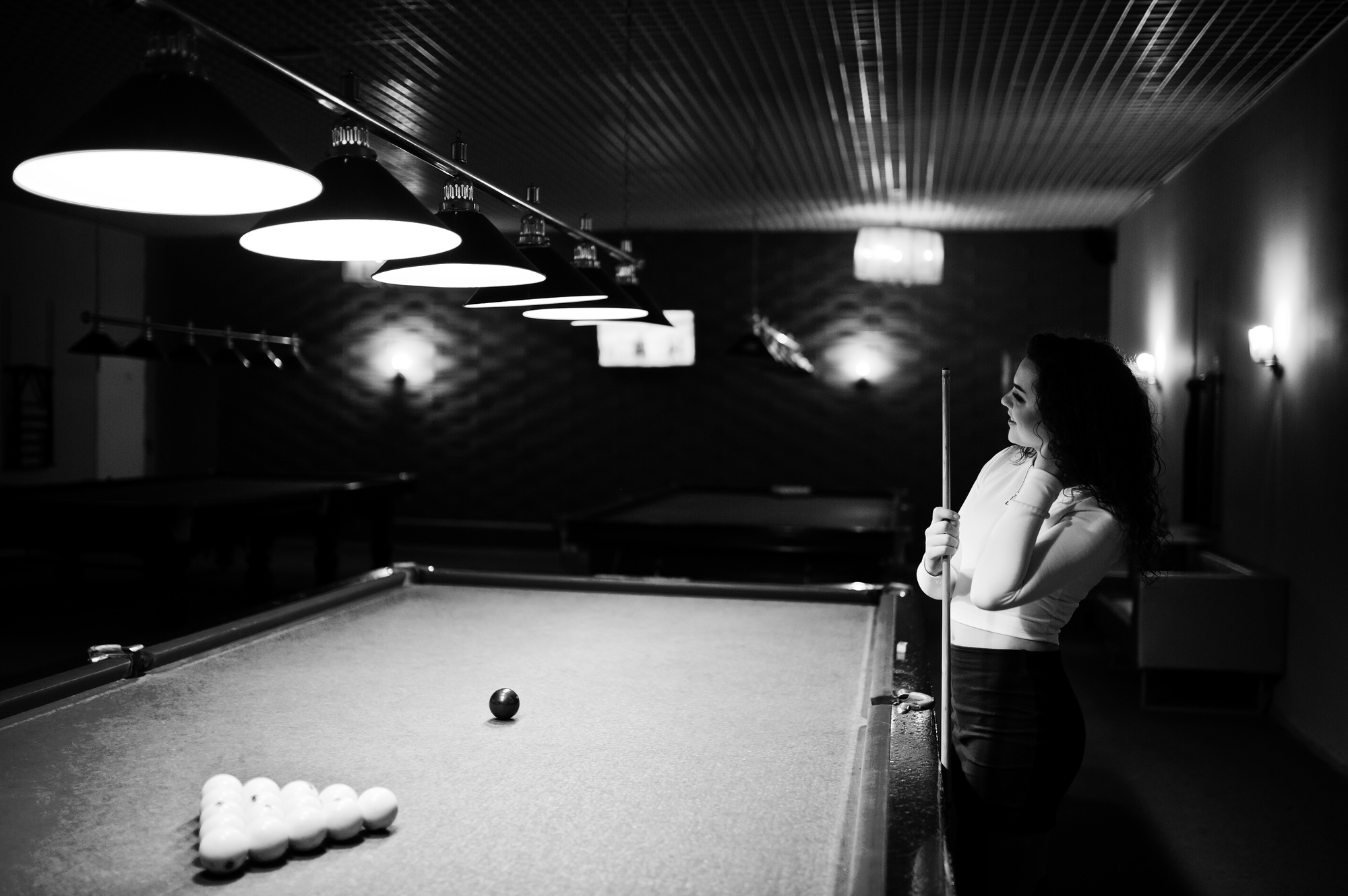 Young curly girl posed near billiard table